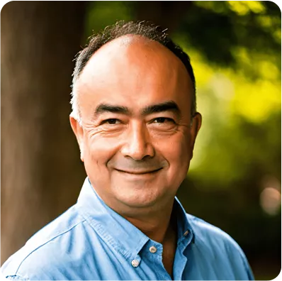 Smiling middle-aged man outdoors wearing a blue shirt with natural background
